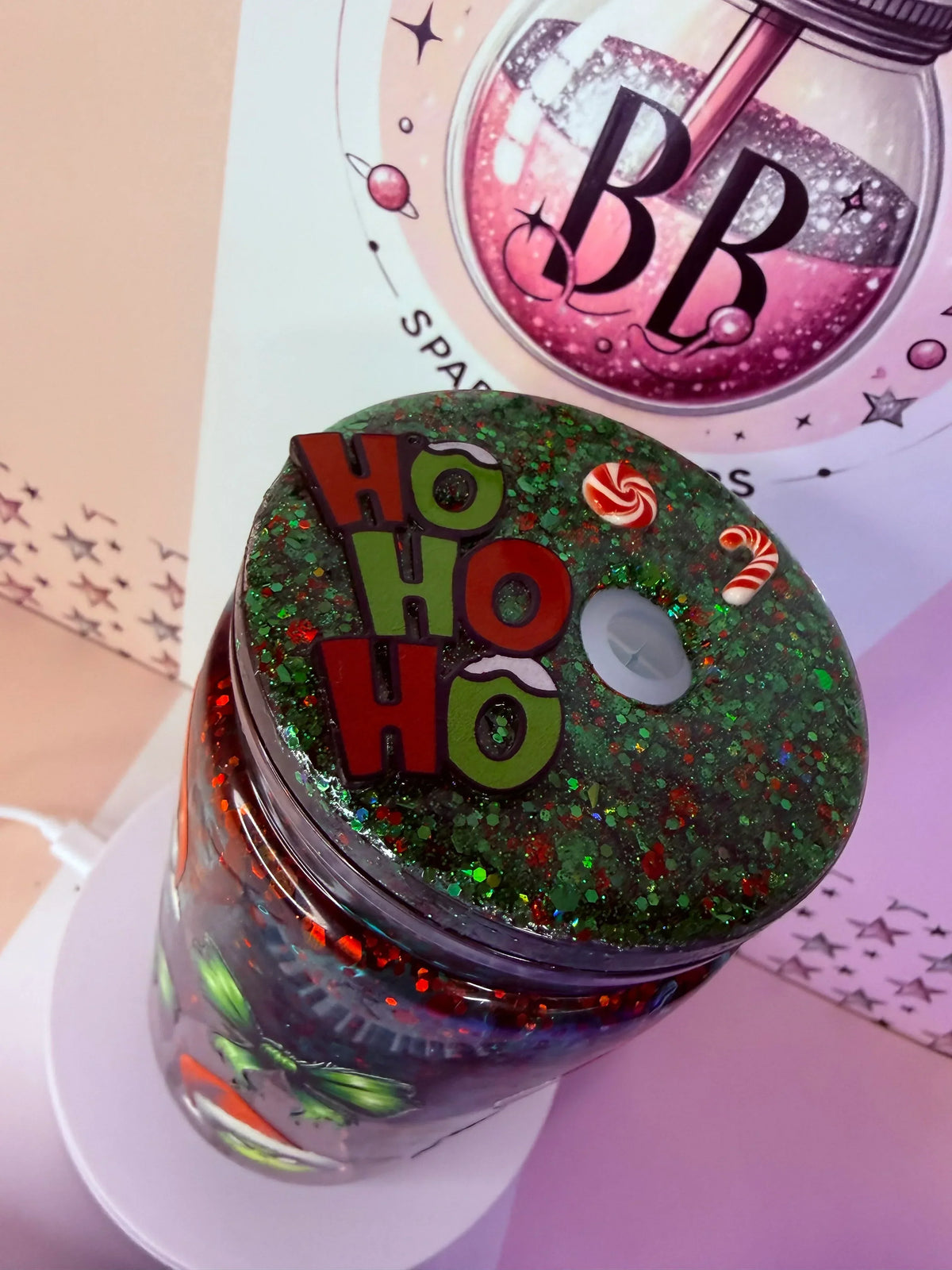 Festive glitter tumbler with 'Ho Ho Ho' lid, candy canes, and holiday sparkle design